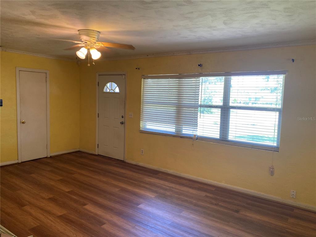 A room with yellow walls, wood-look flooring, a ceiling fan, and a front door — 1040 HAMPTON ROAD, DAYTONA BEACH, FL