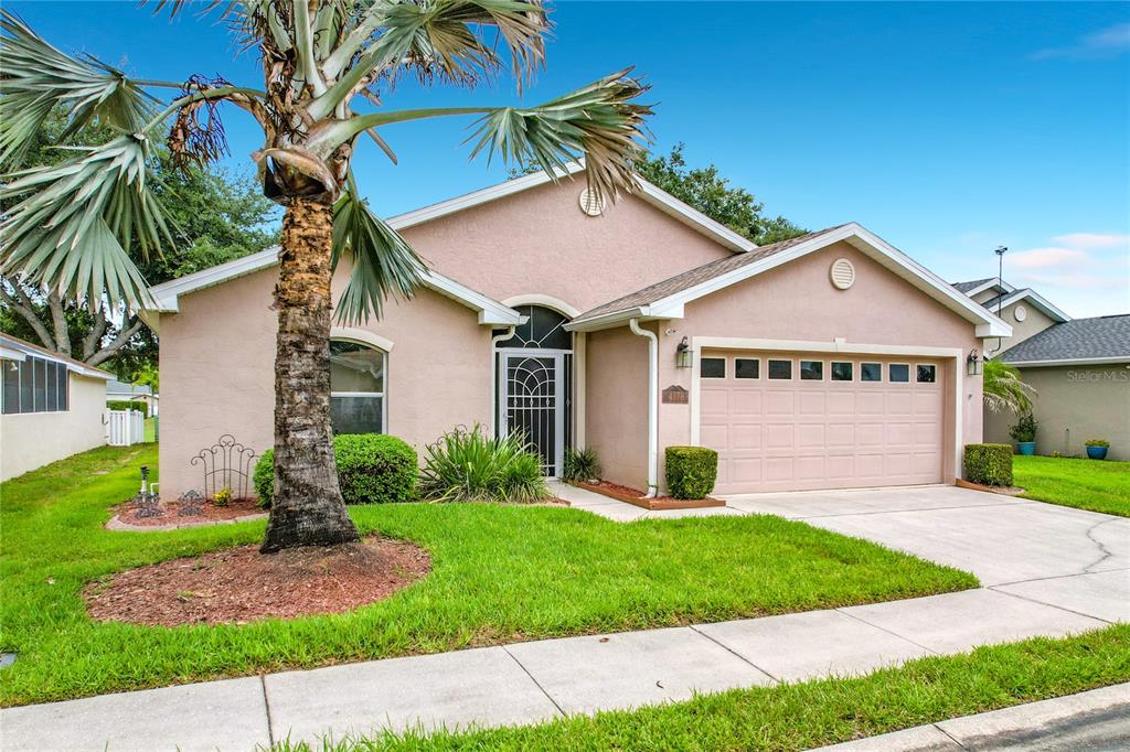 A single-story peach-colored house features a palm tree, a two-car garage, and a front lawn — 4178 CANNES AVENUE, LAKE WALES, FL