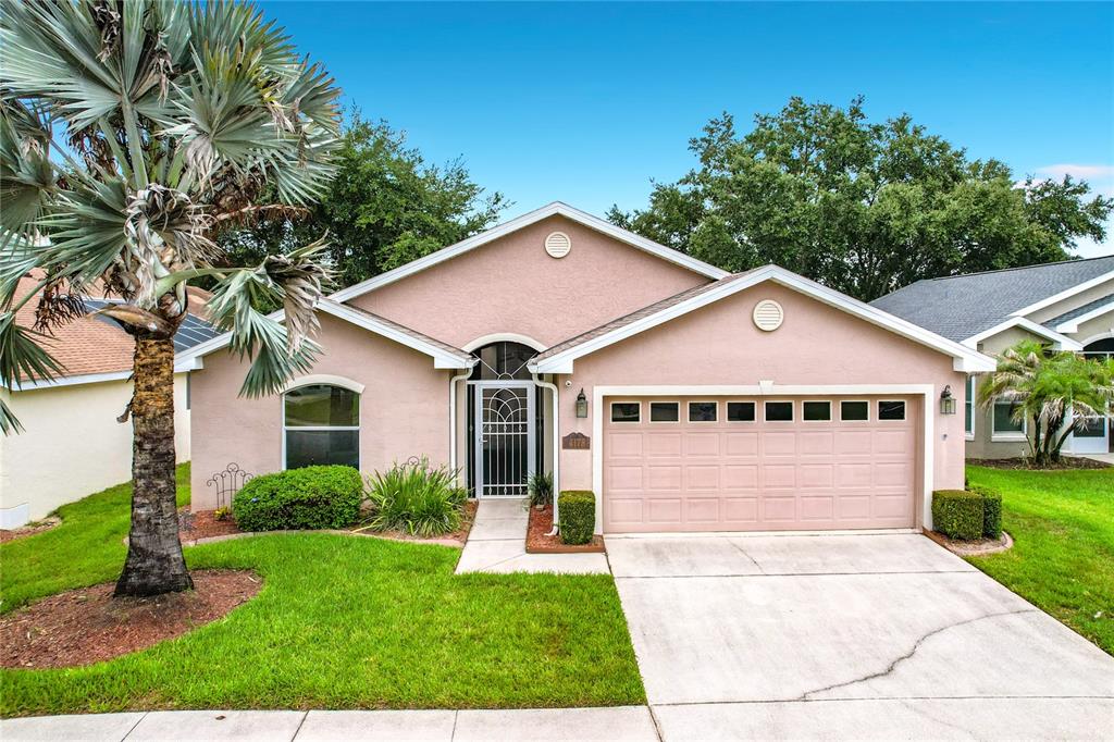 A single-story house with a tan stucco exterior, a two-car garage, and a palm tree — 4178 CANNES AVENUE, LAKE WALES, FL