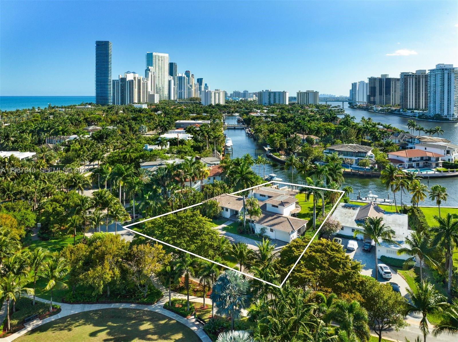 An aerial view shows a waterfront house with a tiled roof surrounded by lush trees — 268 S Parkway, Golden Beach FL 33160, GOLDEN BEACH, FL