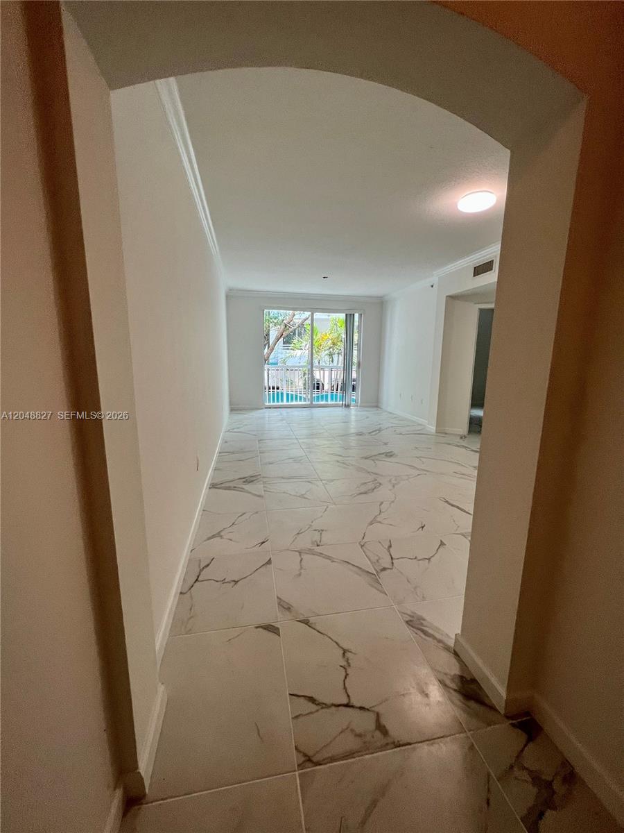 An arched doorway leads into a living area with white marble-patterned tile flooring — 9172 Collins Ave # 214, Surfside FL 33154, SURFSIDE, FL