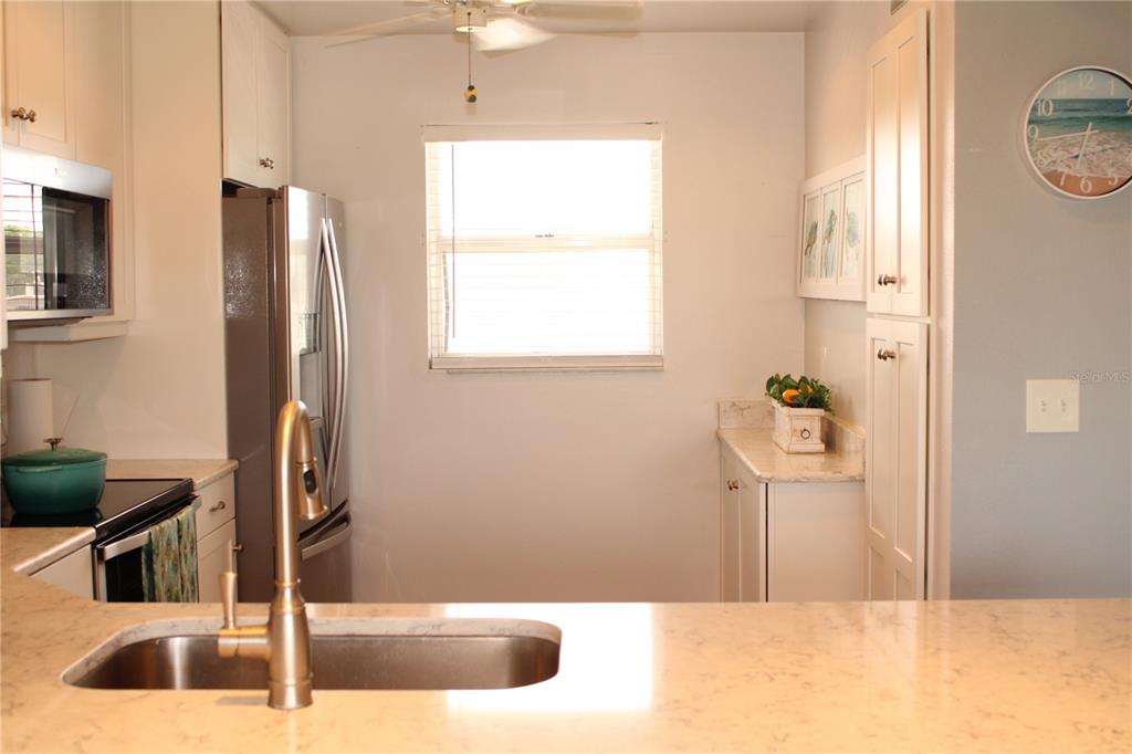 A kitchen features white cabinetry, stainless steel appliances, a sink, and a window — 4240 IRONWOOD CIRCLE UNIT 404, BRADENTON, FL