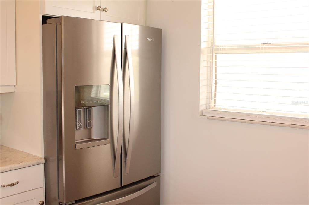 A stainless steel French door refrigerator stands in a kitchen next to a window — 4240 IRONWOOD CIRCLE UNIT 404, BRADENTON, FL