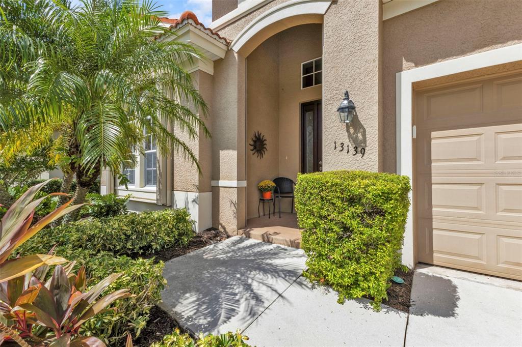 The exterior of a house features a tan stucco facade, a garage, and a front entryway — 13139 PRESERVE COURT, PORT CHARLOTTE, FL