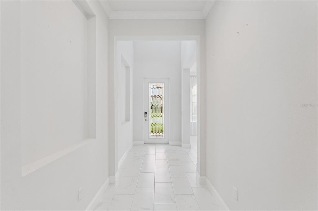 A bright hallway features white walls, a tiled floor, and a decorative glass-paneled front door — 10763 ROYAL CYPRESS WAY, ORLANDO, FL