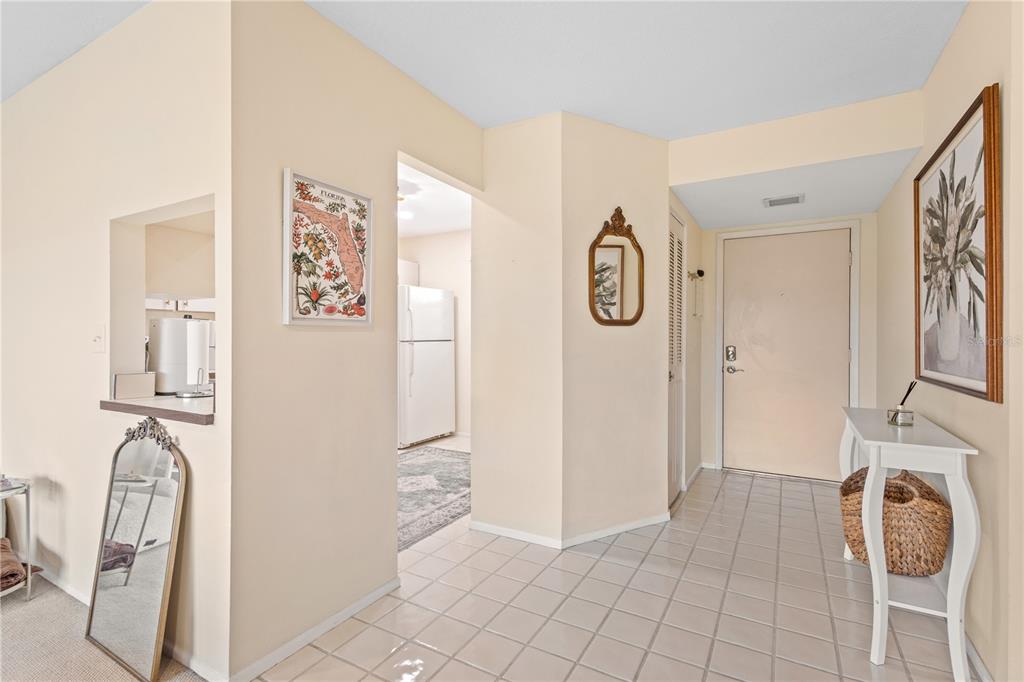 An entryway with tiled flooring leads to a kitchen and a white front door — 3620 IRONWOOD CIRCLE UNIT 302O, BRADENTON, FL