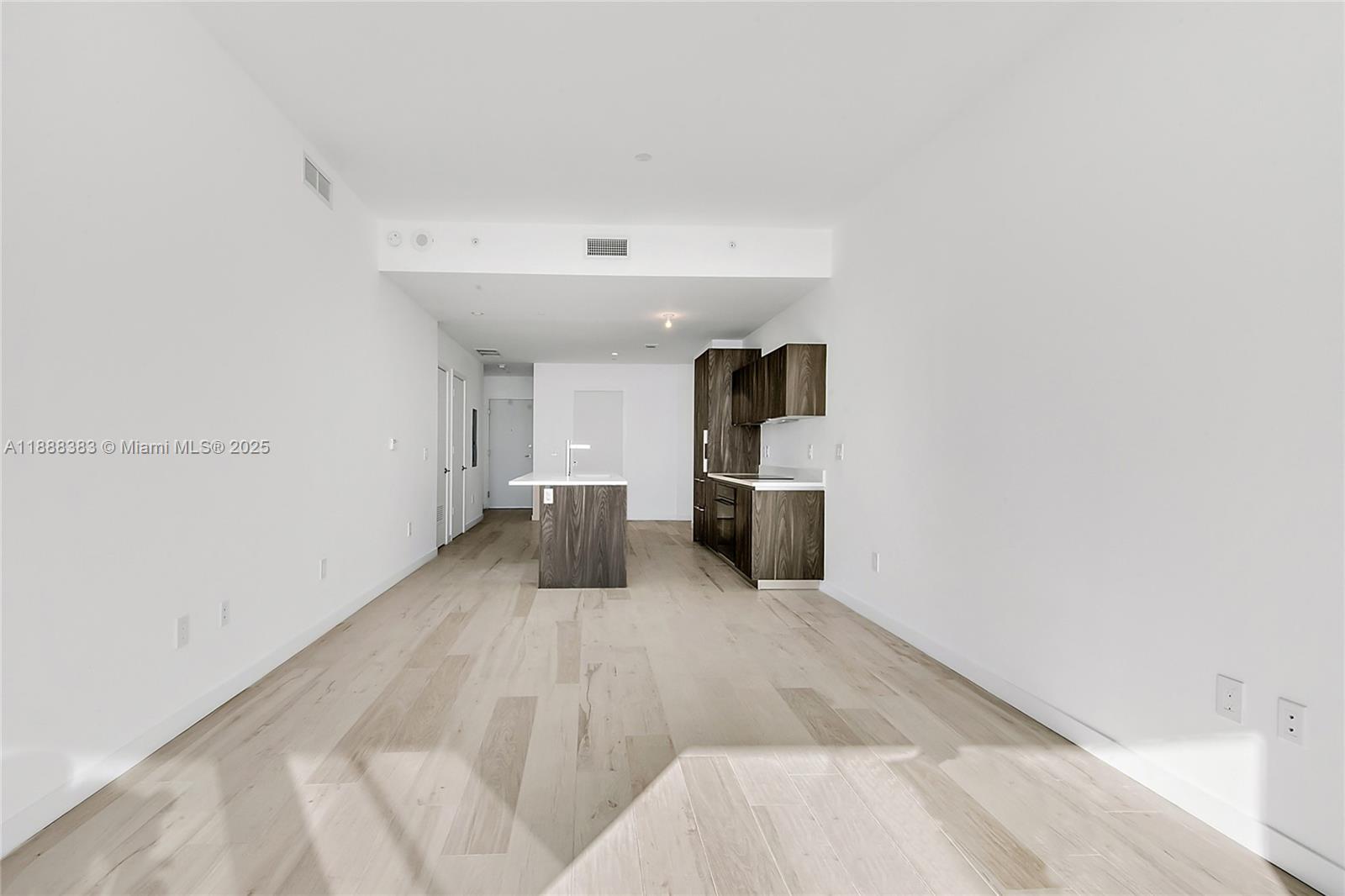 A modern kitchen with dark wood cabinetry and a central island sits in an open-plan room — 480 NE 31st St # 904, Miami FL 33137, MIAMI, FL