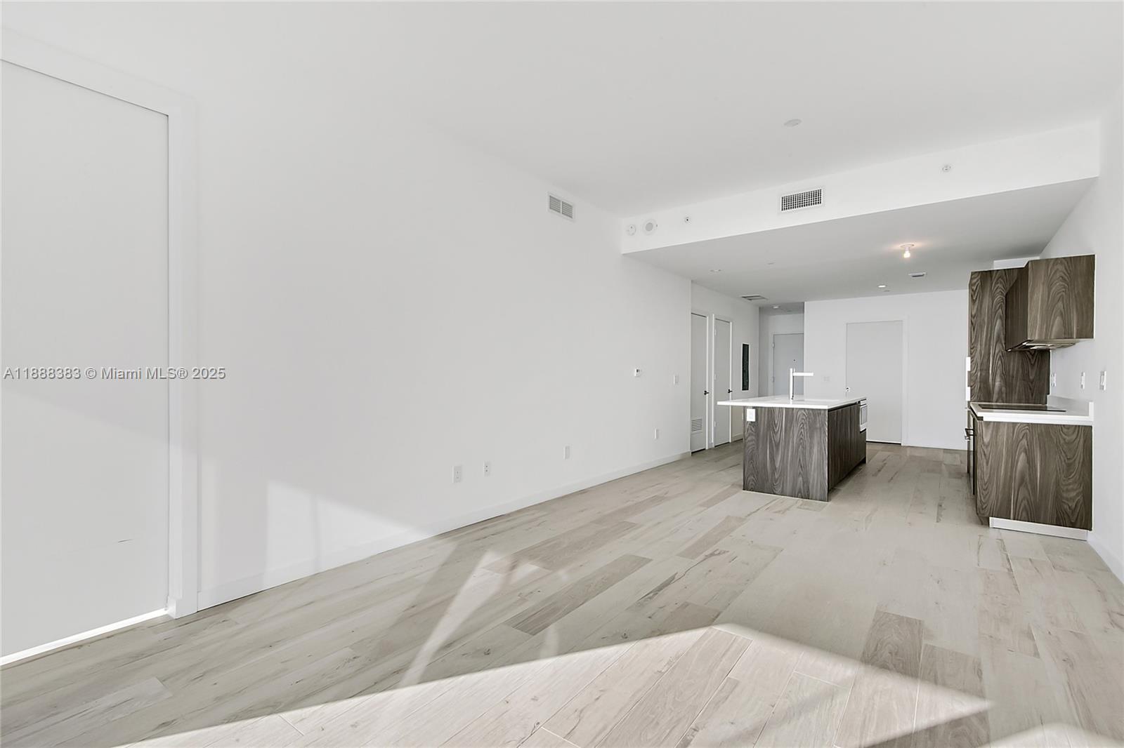 An open-concept kitchen features wood-grain cabinetry and a central island on light wood flooring — 480 NE 31st St # 904, Miami FL 33137, MIAMI, FL