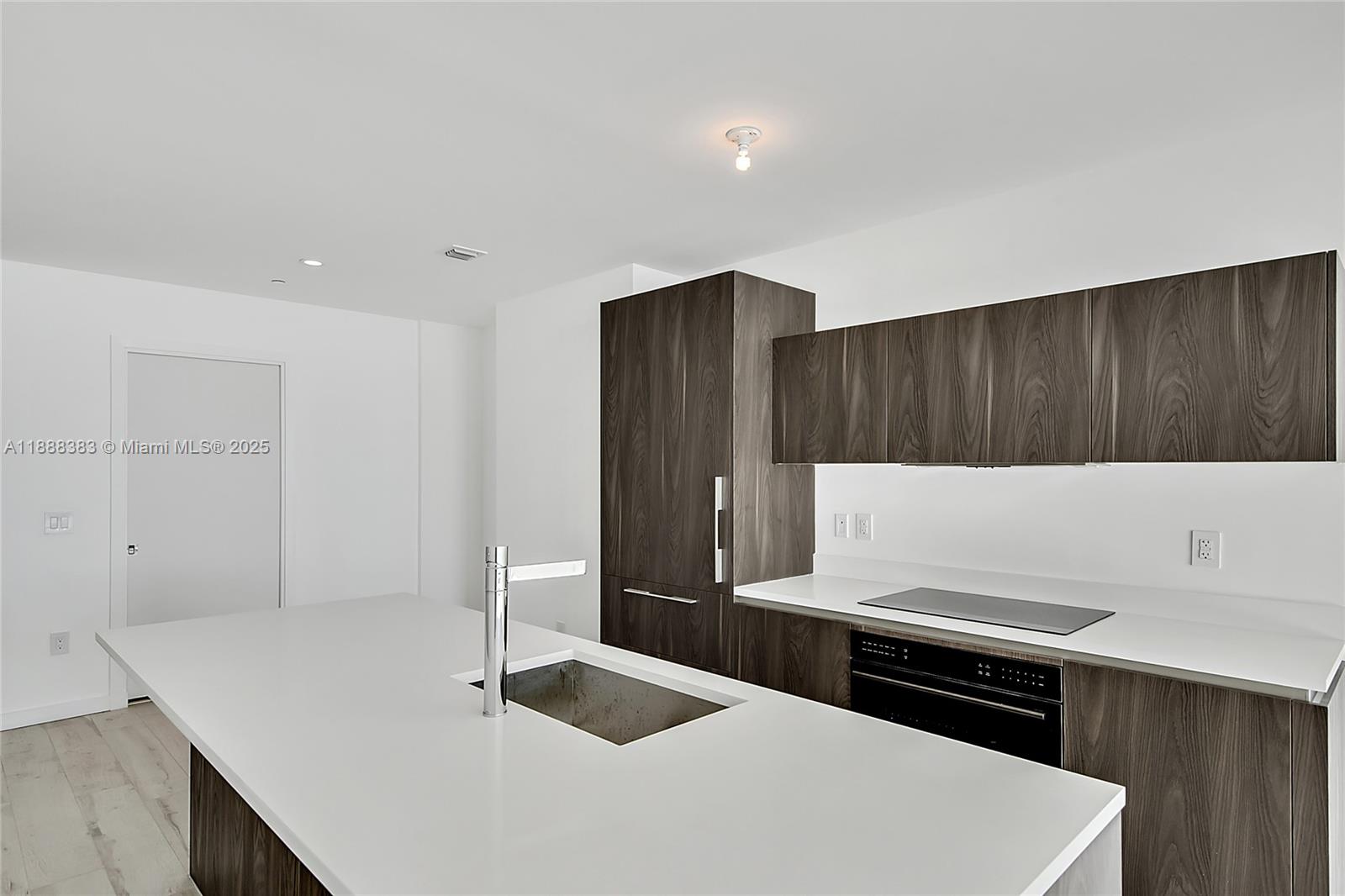 A modern kitchen features dark wood cabinetry, white countertops, and a central island with sink — 480 NE 31st St # 904, Miami FL 33137, MIAMI, FL