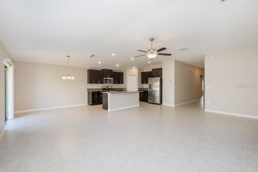 An open-concept kitchen with dark cabinets and a central island overlooks a large living area — 5524 RAINWOOD MEADOWS DRIVE, APOLLO BEACH, FL