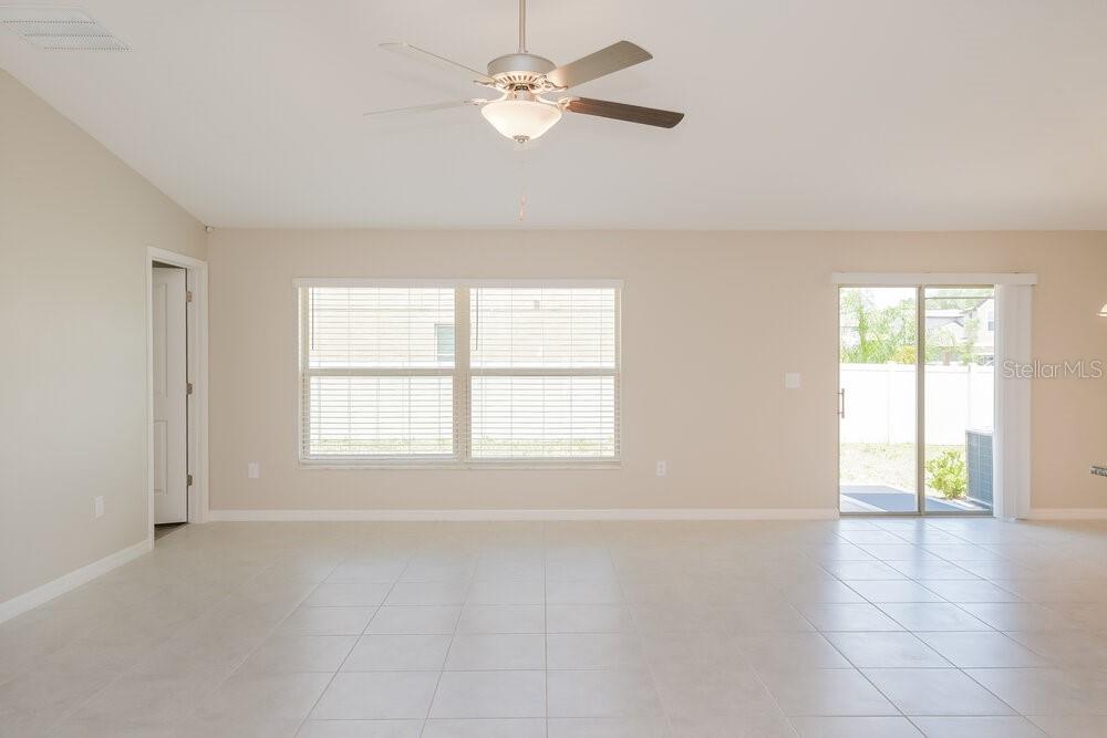 A bright living room with tile flooring, a ceiling fan, and sliding glass patio doors — 5524 RAINWOOD MEADOWS DRIVE, APOLLO BEACH, FL