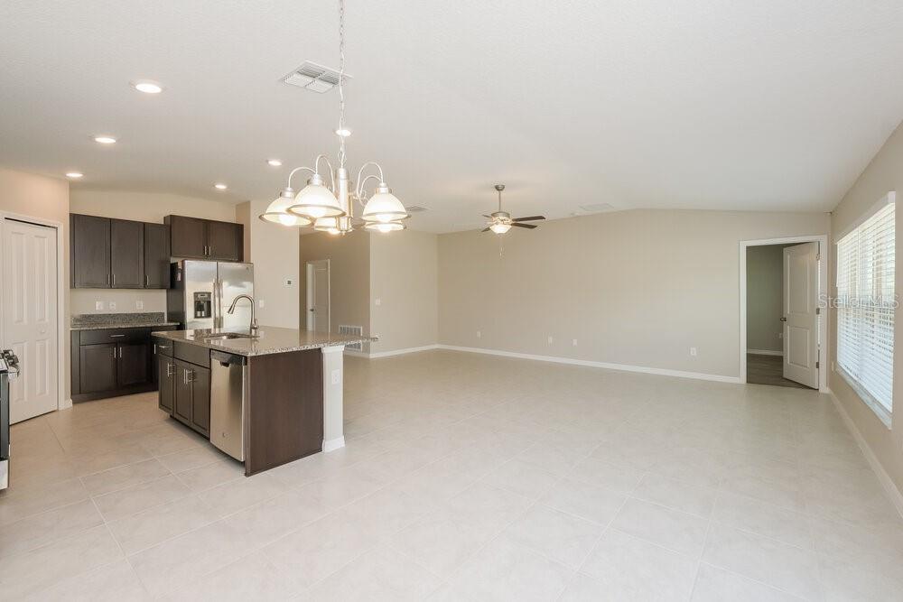 An open-concept kitchen with dark cabinets and a large island overlooks a spacious living area — 5524 RAINWOOD MEADOWS DRIVE, APOLLO BEACH, FL