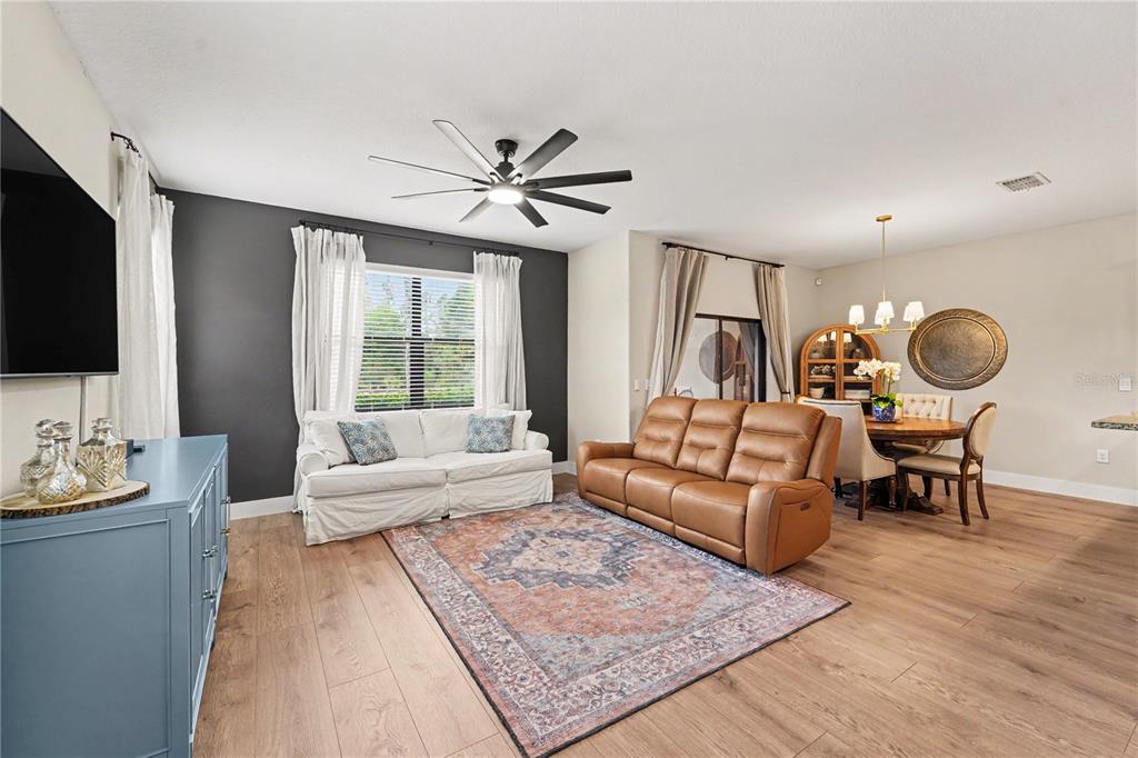 A living room features a brown leather sofa, a white sofa, and a dining area — 28425 PLEASANT BAY LOOP, WESLEY CHAPEL, FL