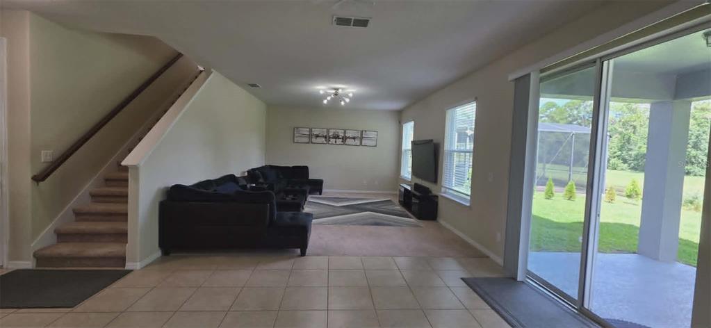 A living room features a staircase, a dark sectional sofa, and sliding glass doors — 5177 DOVE TREE STREET, ORLANDO, FL