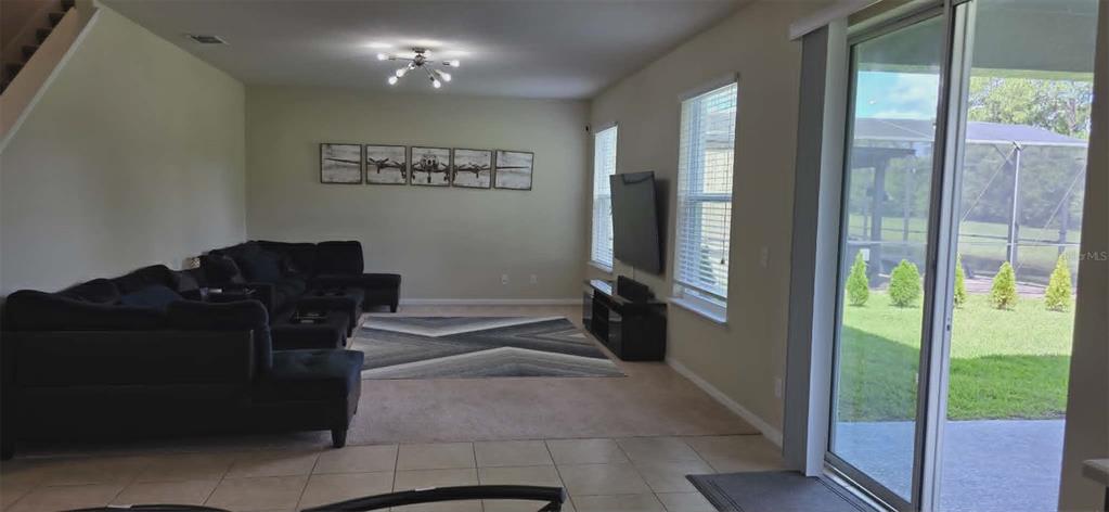 A living room features a large sectional sofa, a television, and a sliding glass door — 5177 DOVE TREE STREET, ORLANDO, FL