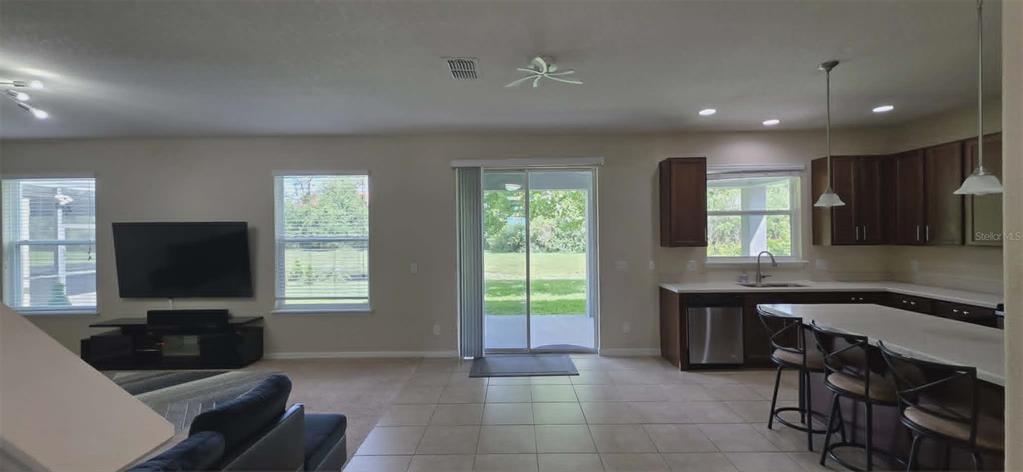 An open-concept living room and kitchen featuring dark wood cabinets and a sliding glass door — 5177 DOVE TREE STREET, ORLANDO, FL