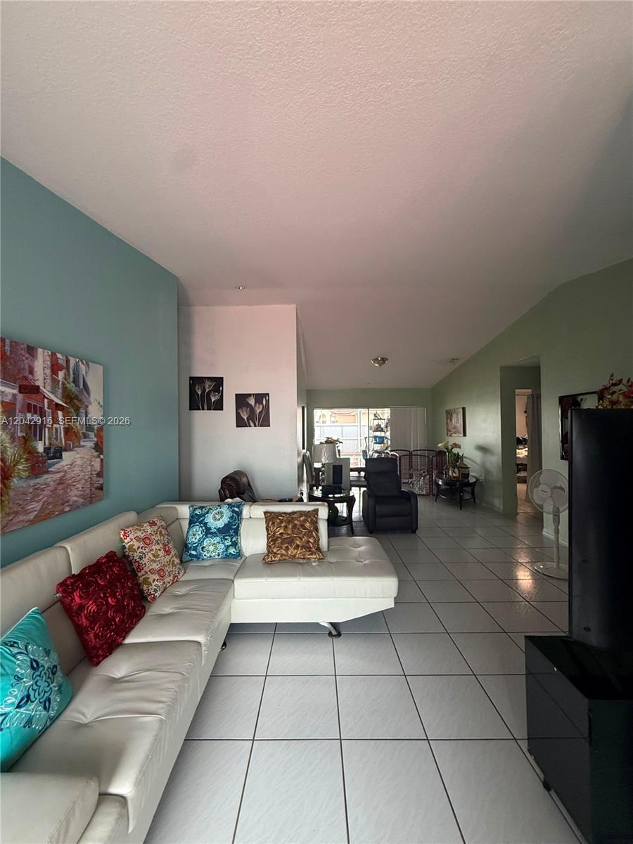 A living room features a white sectional sofa, tiled floors, and light-colored walls — 17401 SW 144th Ct, Miami FL 33177, MIAMI, FL
