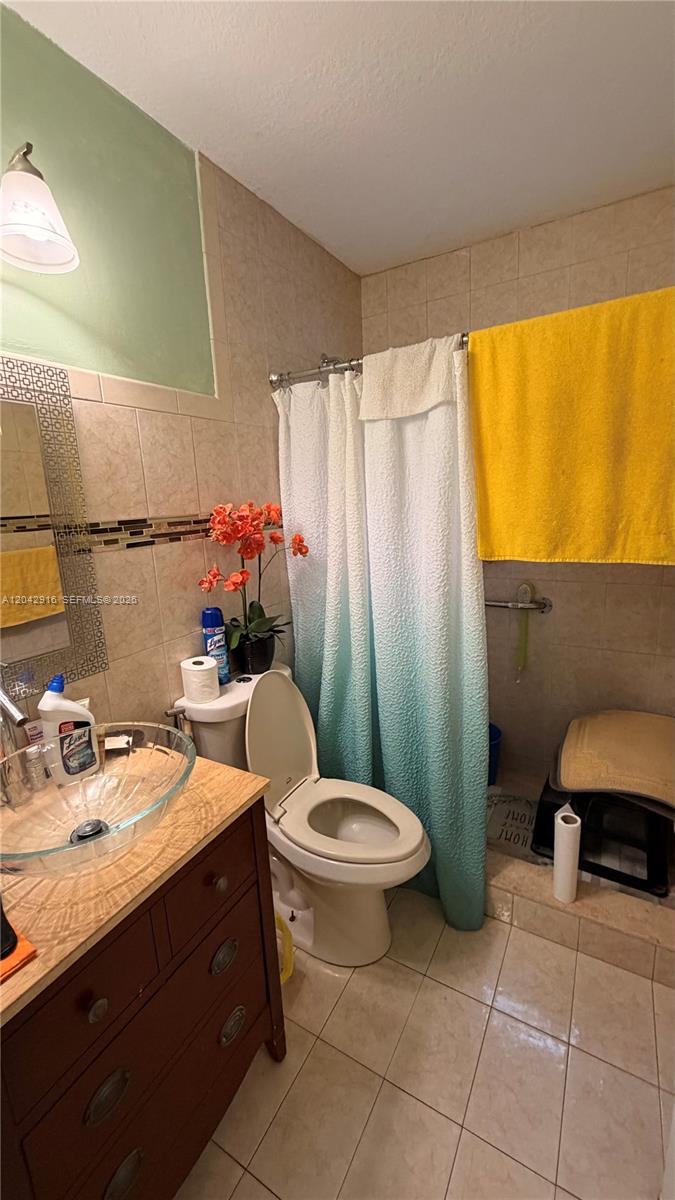 A bathroom features a glass vessel sink, a toilet, and a blue-to-white ombre shower curtain — 17401 SW 144th Ct, Miami FL 33177, MIAMI, FL