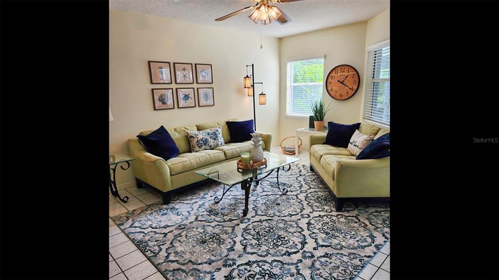 A living room features two light green sofas, a glass coffee table, and a patterned rug — 1318 SIESTA BAYSIDE DRIVE UNIT C, SARASOTA, FL