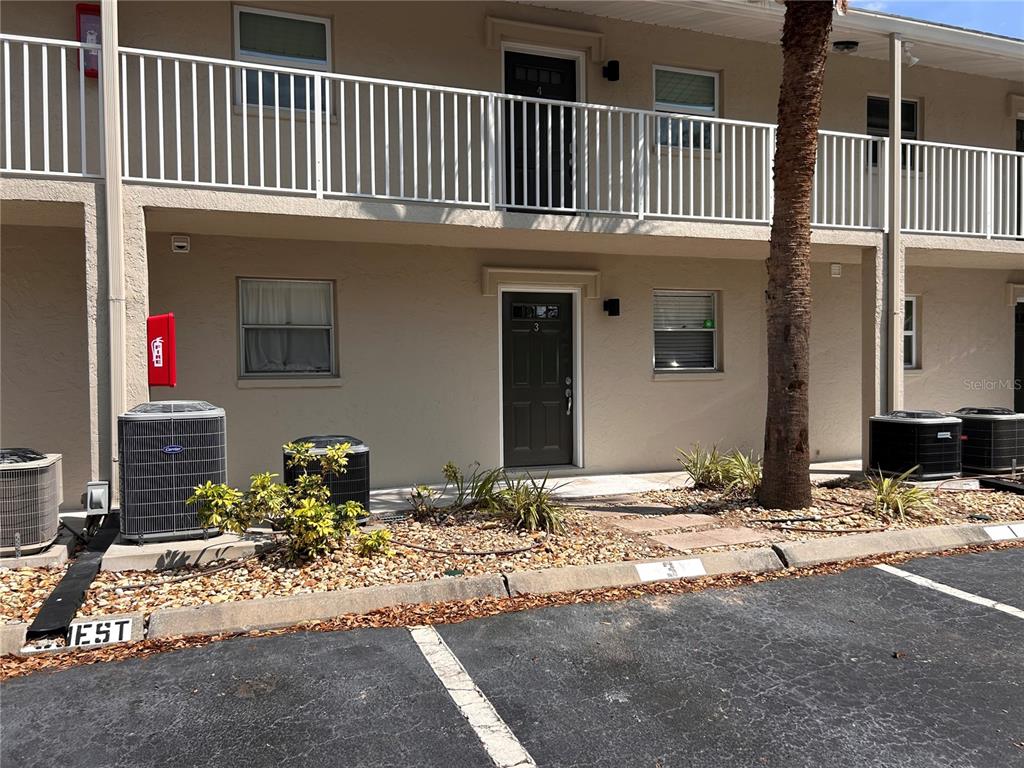 The exterior of a two-story apartment building features a parking lot, air conditioning units, and balconies — 972 LA COSTA CIRCLE UNIT 3, SARASOTA, FL
