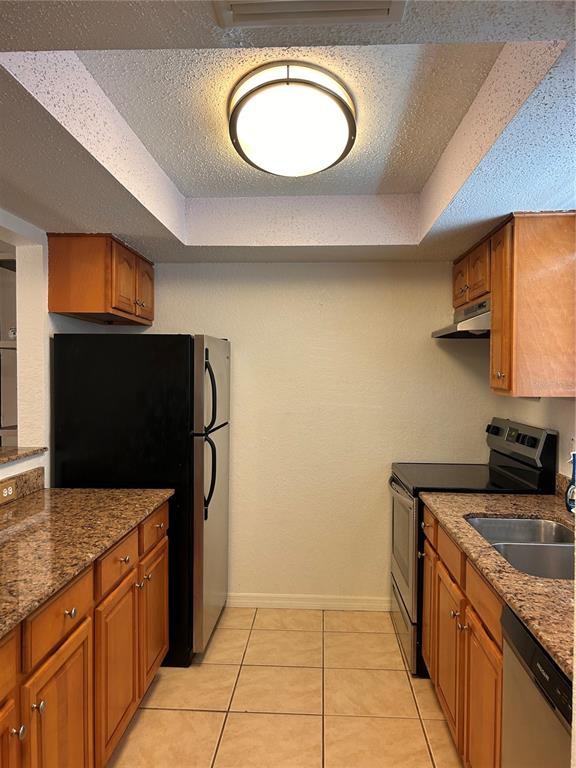 A kitchen features wood cabinets, granite countertops, stainless steel appliances, and a recessed ceiling light — 972 LA COSTA CIRCLE UNIT 3, SARASOTA, FL
