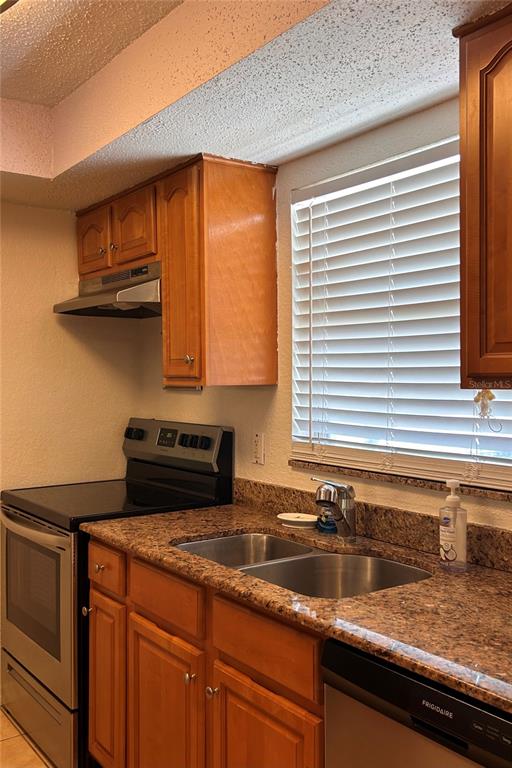 A kitchen features wood cabinets, granite countertops, stainless steel appliances, and a window with blinds — 972 LA COSTA CIRCLE UNIT 3, SARASOTA, FL