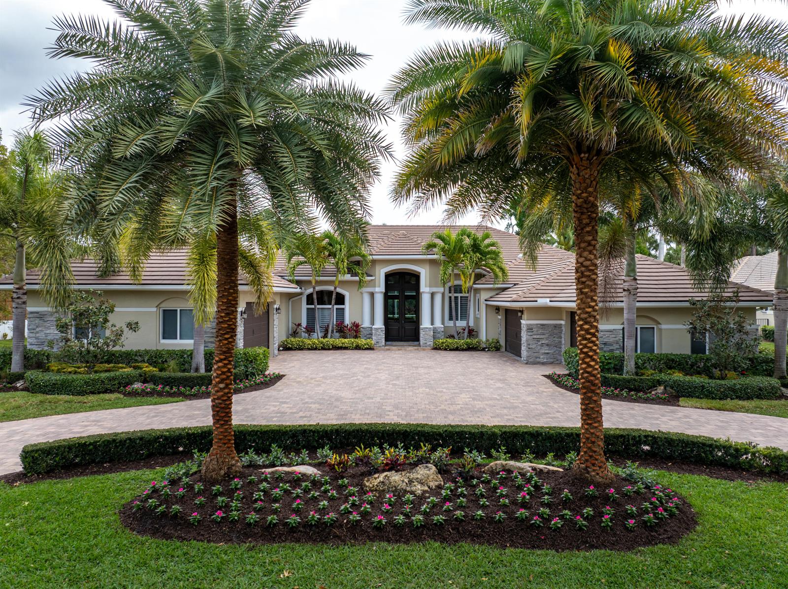 A single-story house with a paved driveway, palm trees, and a landscaped front garden — 1209 Breakers West Boulevard, West Palm Beach FL 33411, WEST PALM BEACH, FL