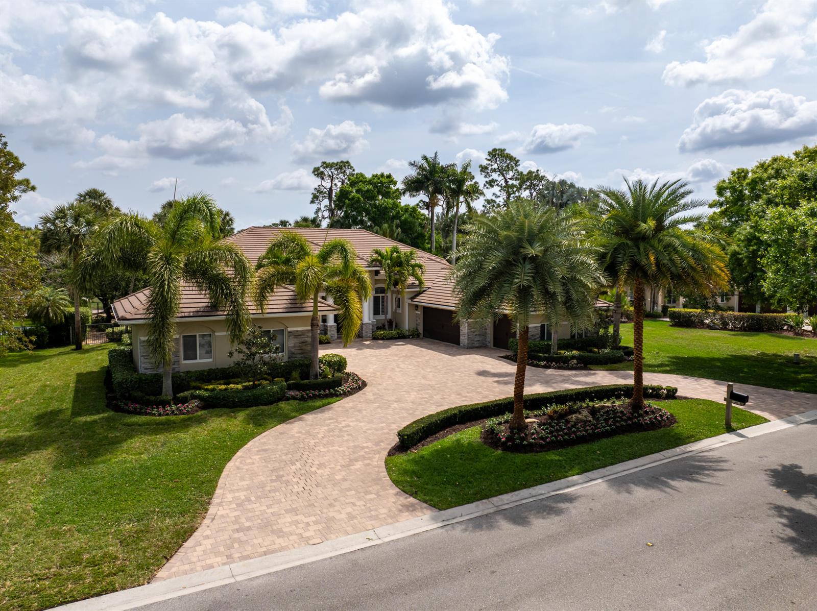 A single-story house with a paved driveway, palm trees, and a landscaped front yard — 1209 Breakers West Boulevard, West Palm Beach FL 33411, WEST PALM BEACH, FL