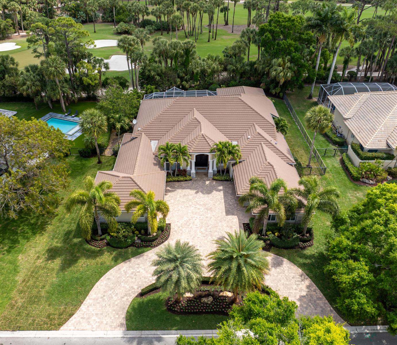 An aerial view shows a single-story house with a tiled roof, circular driveway, and pool — 1209 Breakers West Boulevard, West Palm Beach FL 33411, WEST PALM BEACH, FL