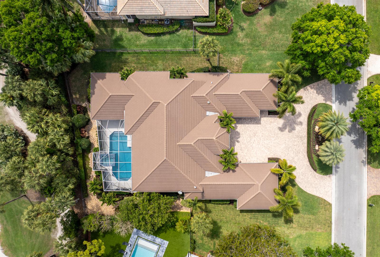 An aerial view shows a house with a brown tile roof, pool cage, and driveway — 1209 Breakers West Boulevard, West Palm Beach FL 33411, WEST PALM BEACH, FL