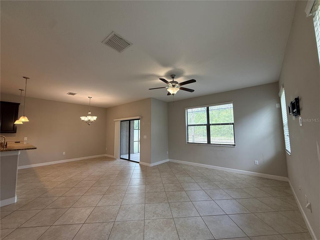 A spacious living and dining area with tile floors, a ceiling fan, and sliding doors — 28423 PLEASANT BAY LOOP, WESLEY CHAPEL, FL