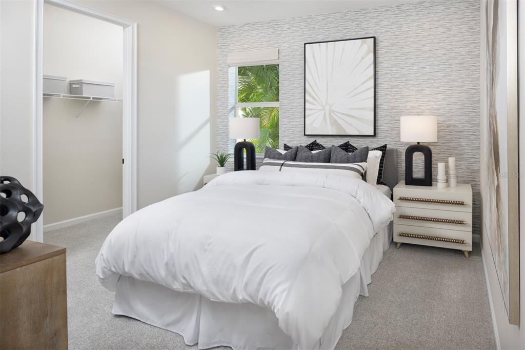 A bedroom features a white bed, textured wallpaper, a window, and a walk-in closet — 11407 BOUNDLESS TERRACE, VENICE, FL
