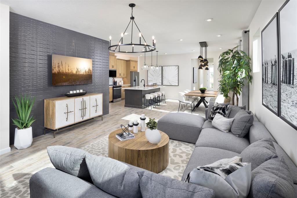A modern open-concept living room features a textured dark accent wall and a gray sectional — 11407 BOUNDLESS TERRACE, VENICE, FL