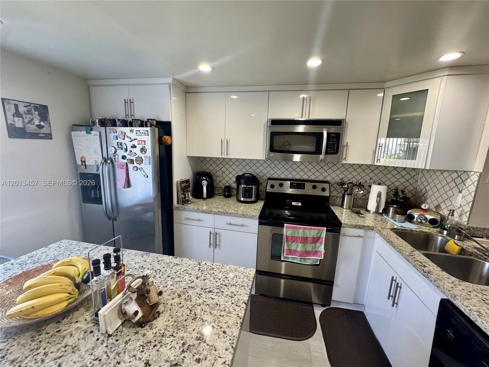 A kitchen features white cabinets, granite countertops, stainless steel appliances, and a patterned tile backsplash — 1481 SW 124th Ct # C, Miami FL 33184, MIAMI, FL
