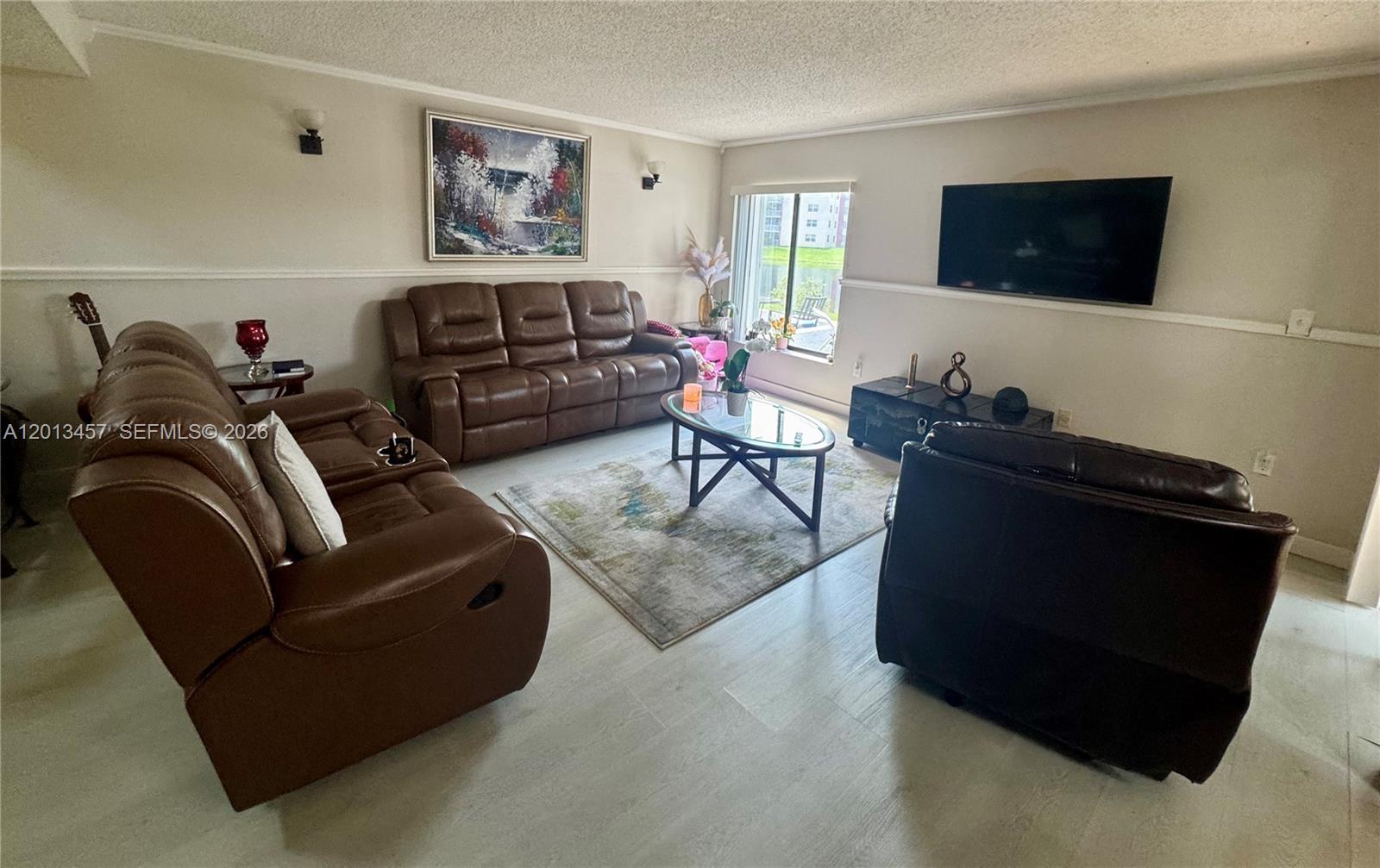 A living room features brown leather furniture, a glass coffee table, and a wall-mounted television — 1481 SW 124th Ct # C, Miami FL 33184, MIAMI, FL