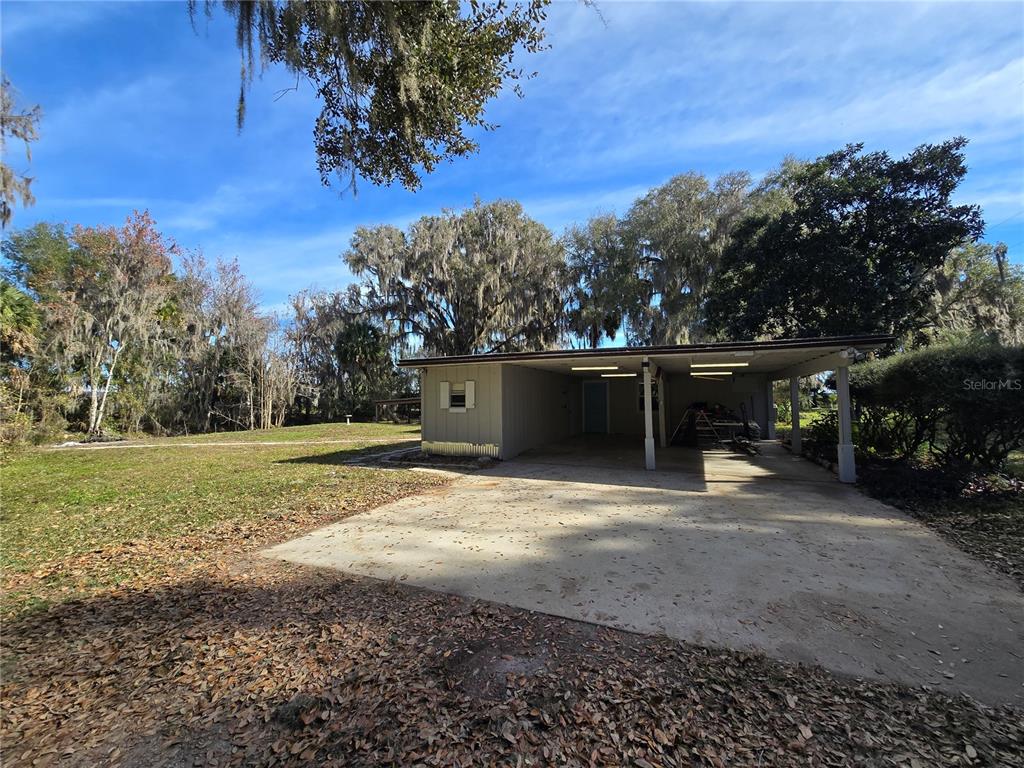 A single-story house with a large attached carport sits on a grassy, tree-filled lot — 2346 CR 401, LAKE PANASOFFKEE, FL
