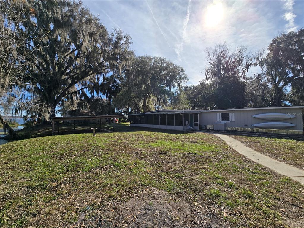 A single-story house with a screened porch and a boat shelter near a lake — 2346 CR 401, LAKE PANASOFFKEE, FL