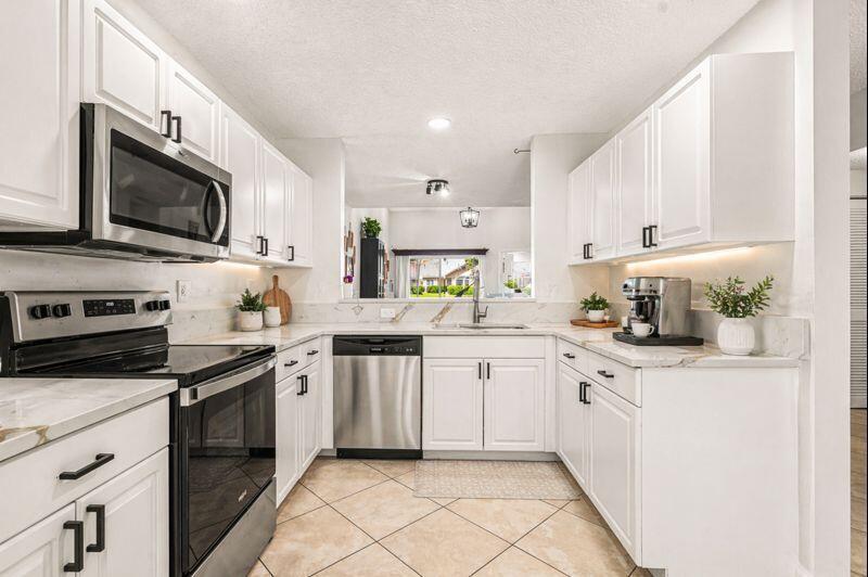 A white kitchen features stainless steel appliances, marble-look countertops, and light-colored tile flooring — 7375 NW 61st Terrace # 19, Parkland FL 33067, PARKLAND, FL