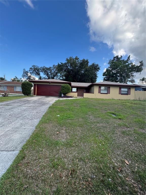 A single-story house with a tan exterior, a brown roof, and a large concrete driveway — 5816 VIKING ROAD, ORLANDO, FL