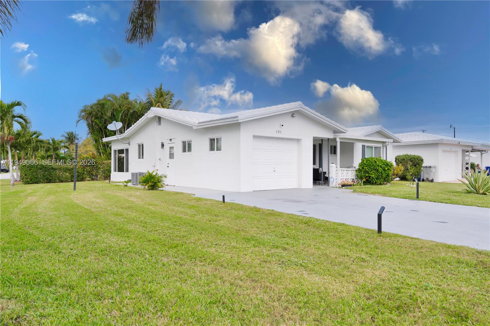 A white single-story house with a garage and driveway sits on a grassy lawn — 131 NW 31st Ct, Pompano Beach FL 33064, POMPANO BEACH, FL