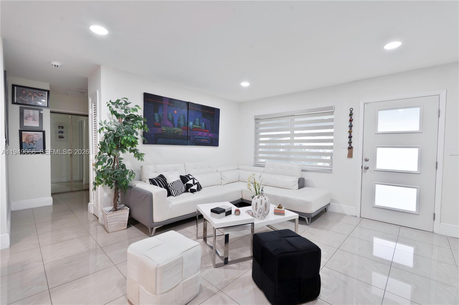 A modern living room features a white sectional sofa, tiled floors, and a front door — 131 NW 31st Ct, Pompano Beach FL 33064, POMPANO BEACH, FL