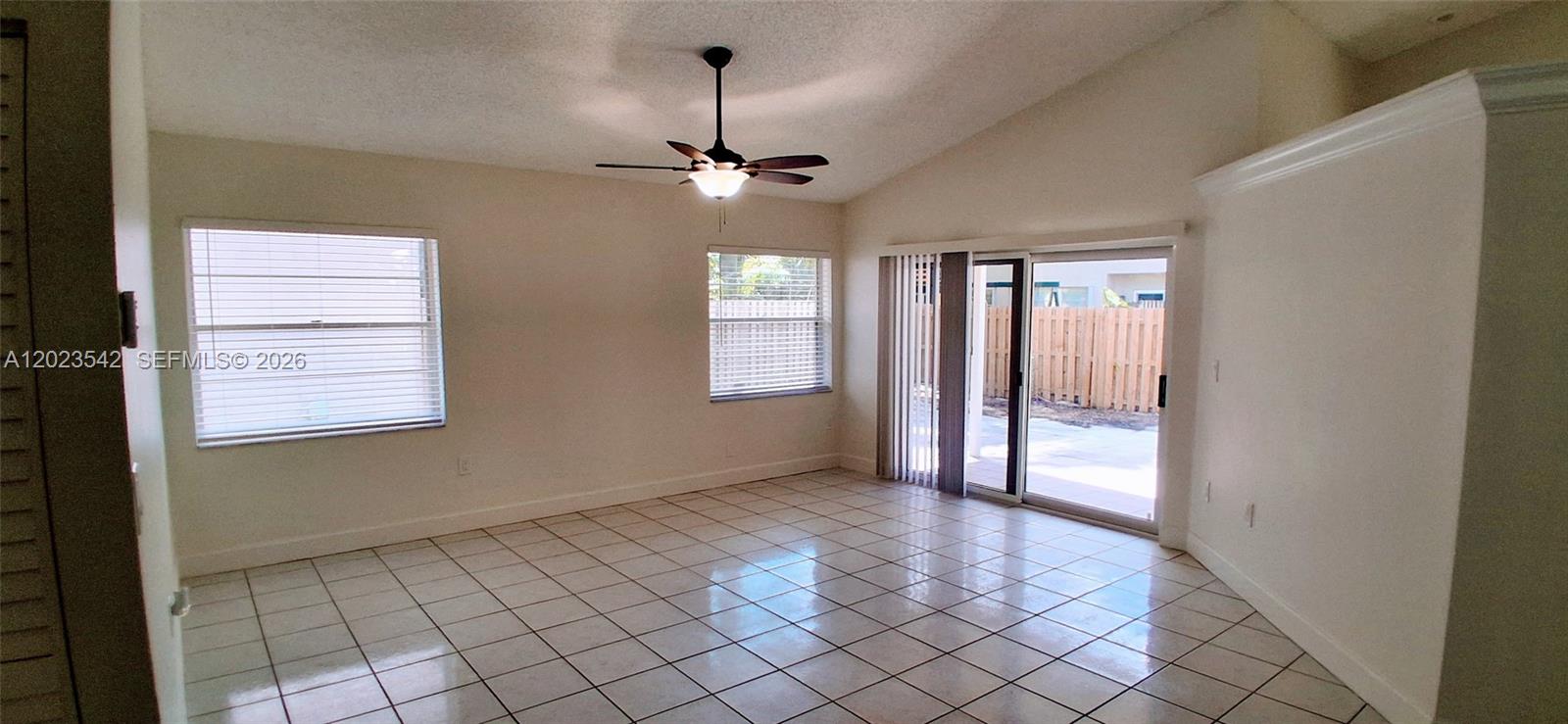 An empty room features white walls, tile flooring, a ceiling fan, and sliding glass doors — 3277 NW 123rd Ave, Sunrise FL 33323, SUNRISE, FL