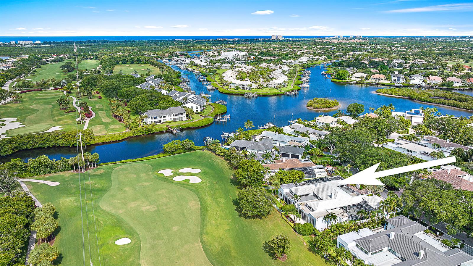 An aerial view shows a white house with a pool cage bordering a golf course — 114 Waters Edge Drive, Jupiter FL 33477, JUPITER, FL