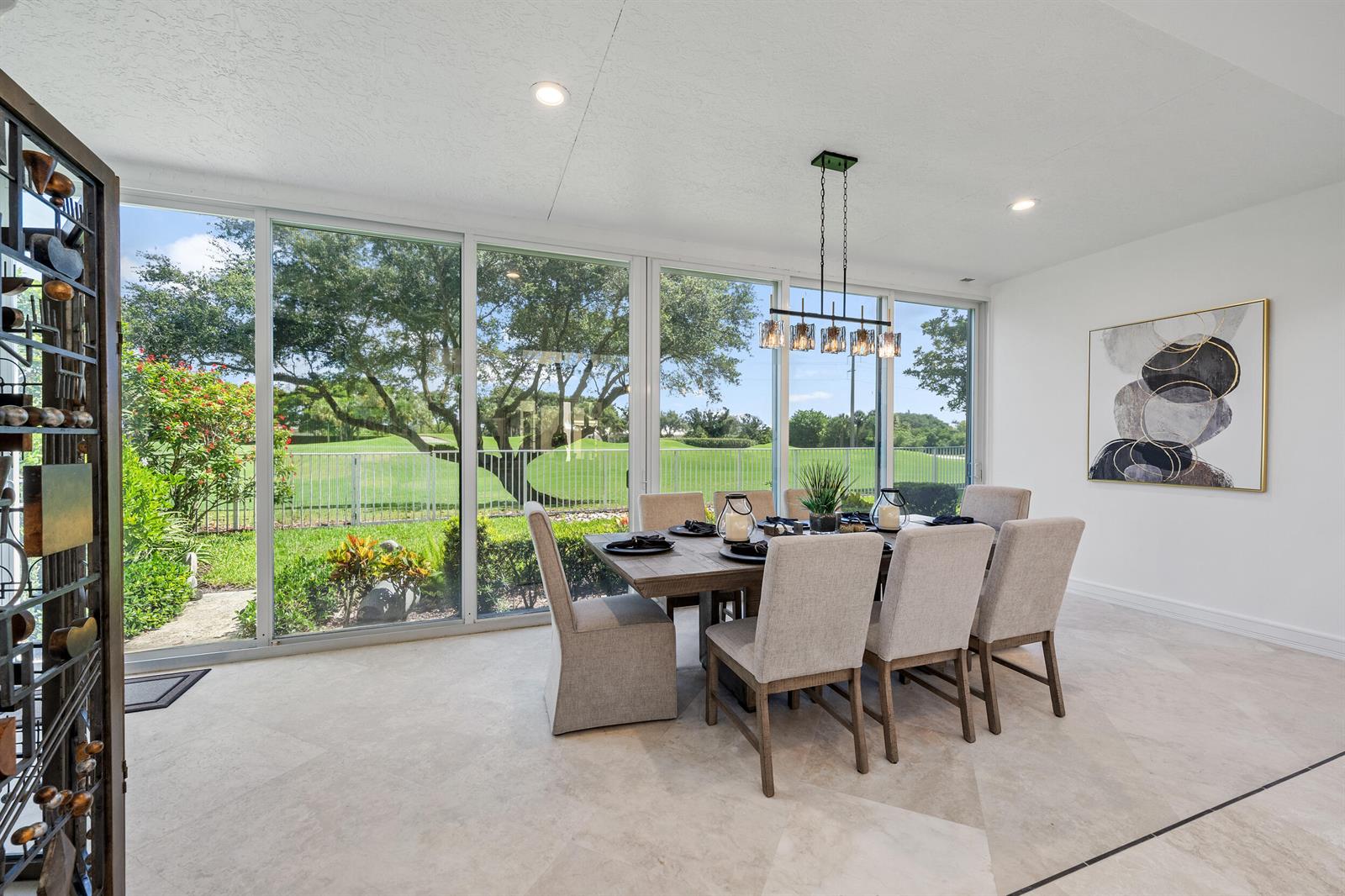 A dining room with a wooden table, upholstered chairs, and large windows overlooking a golf course — 114 Waters Edge Drive, Jupiter FL 33477, JUPITER, FL