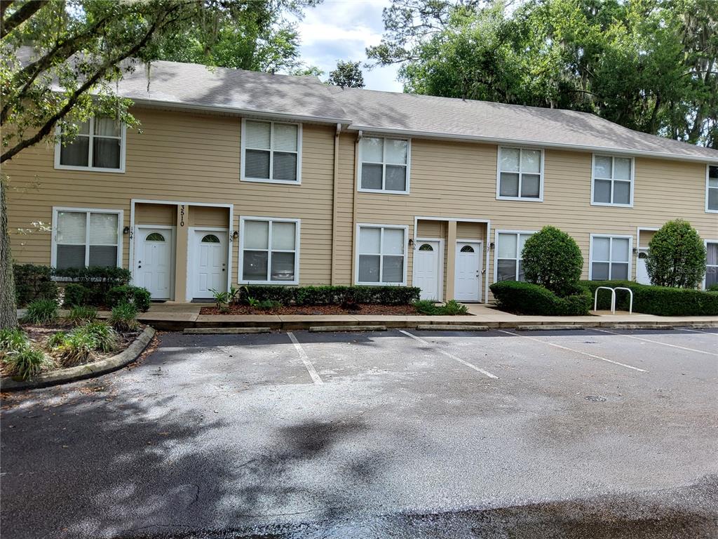 A two-story tan apartment building with white trim and a parking lot in front — 3510 SW 30TH WAY UNIT 156, GAINESVILLE, FL