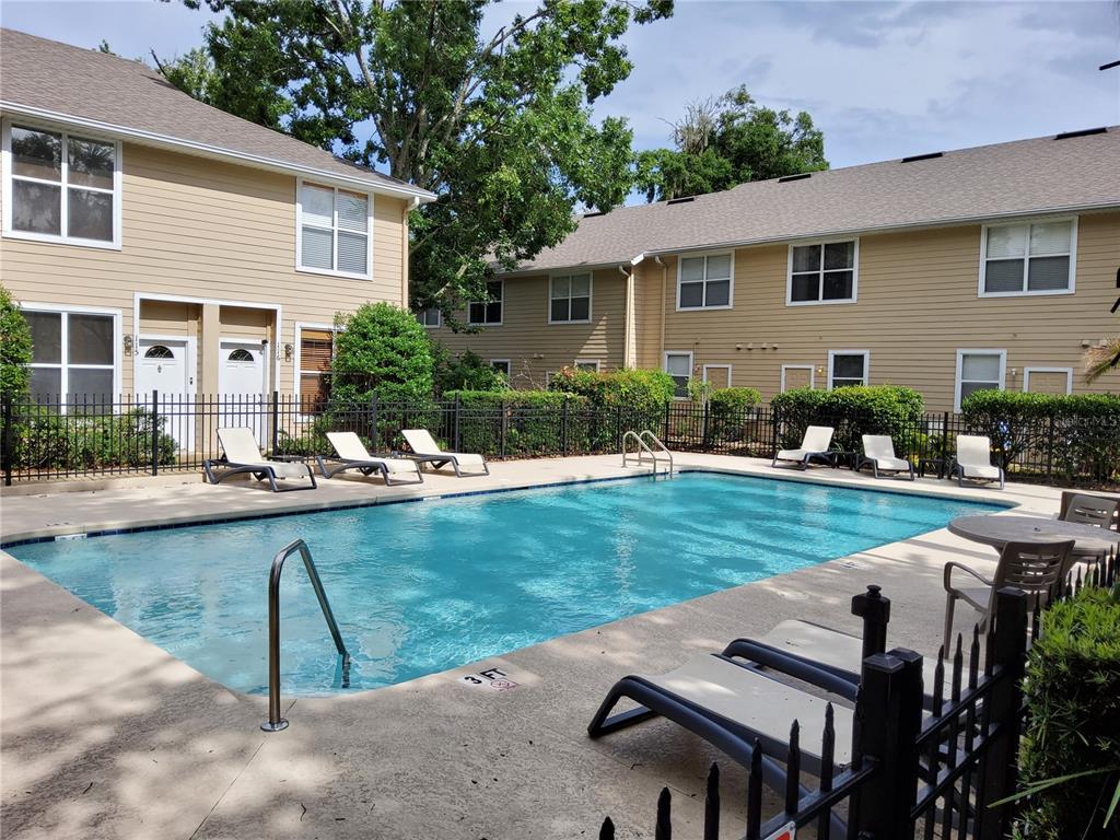 A rectangular swimming pool is surrounded by lounge chairs and tan apartment buildings — 3510 SW 30TH WAY UNIT 156, GAINESVILLE, FL