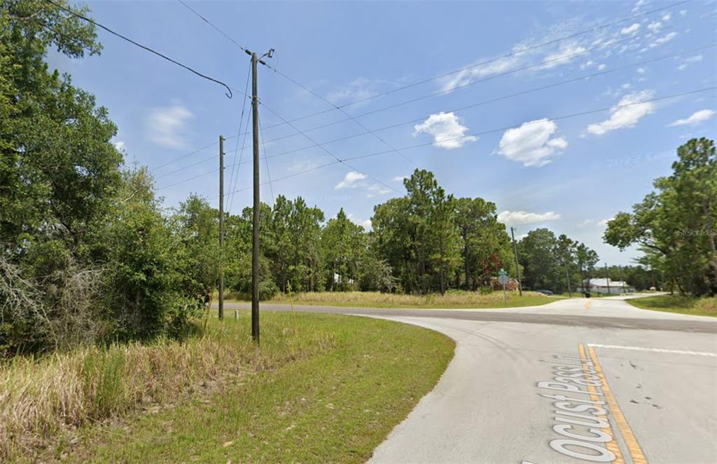 A view of a paved road intersection surrounded by trees and utility poles — lot 19 LOCUST PASS LANE, OCALA, FL