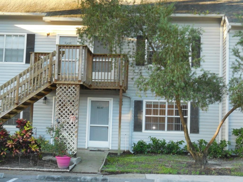 A two-story townhouse exterior features light gray siding, a wooden staircase, and a balcony — 5607 67TH AVENUE N UNIT 314, PINELLAS PARK, FL