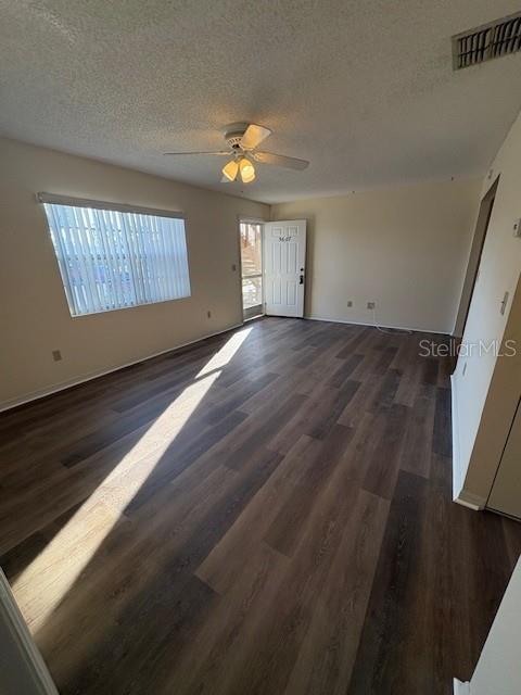 An empty living room features wood-look flooring, a ceiling fan, and a white entry door — 5607 67TH AVENUE N UNIT 314, PINELLAS PARK, FL