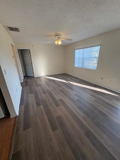An empty room features wood-look flooring, a ceiling fan, and a window with blinds — 5607 67TH AVENUE N UNIT 314, PINELLAS PARK, FL